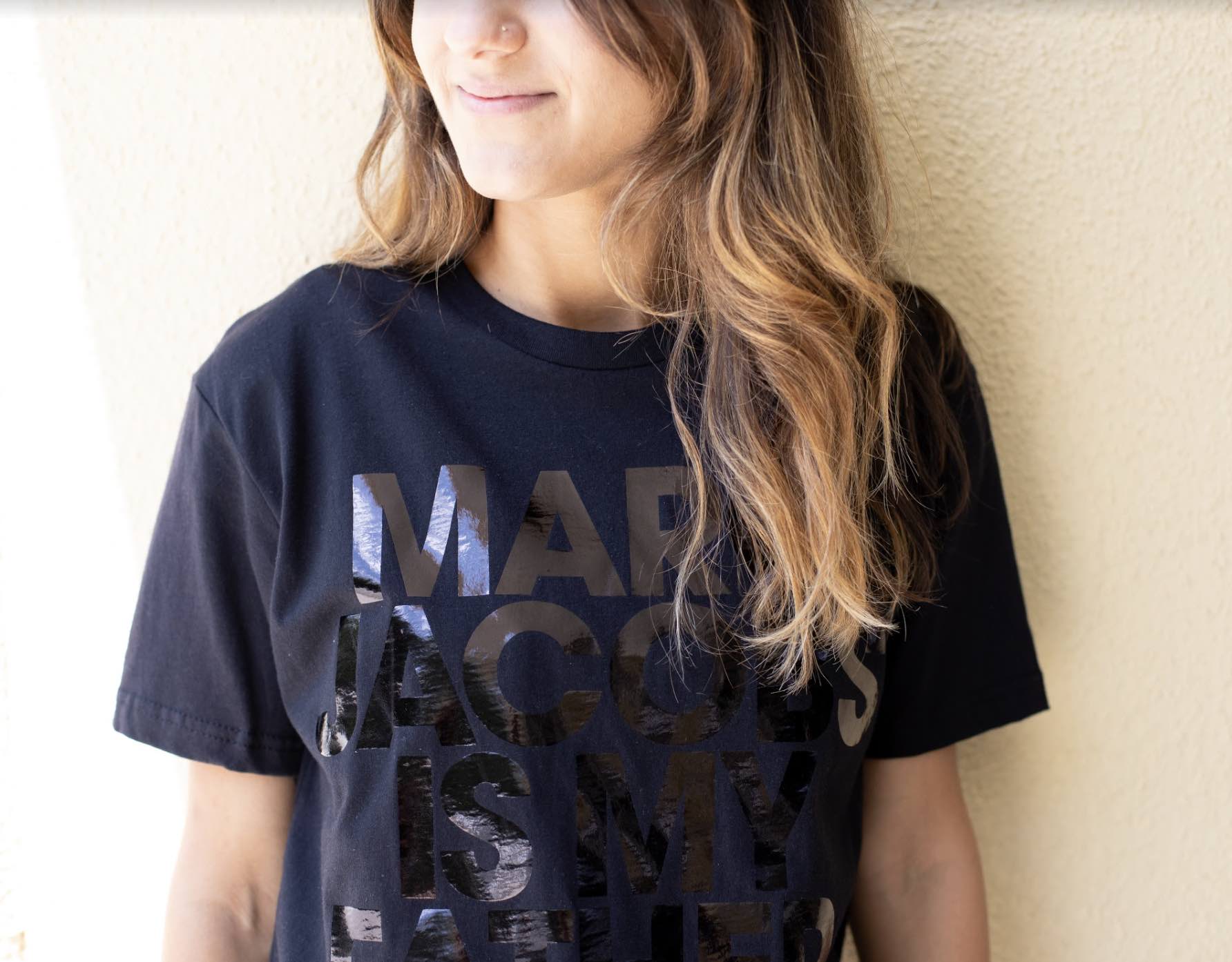 A girl wears a black shirt with a black foil design.