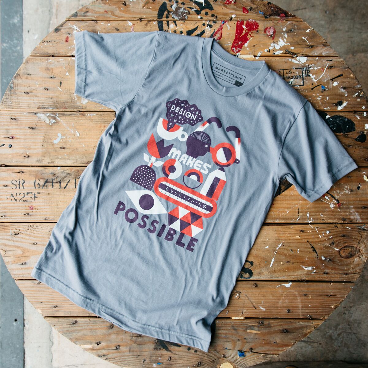 Light blue shirt with multiple red, white and blue designs on a wooden table