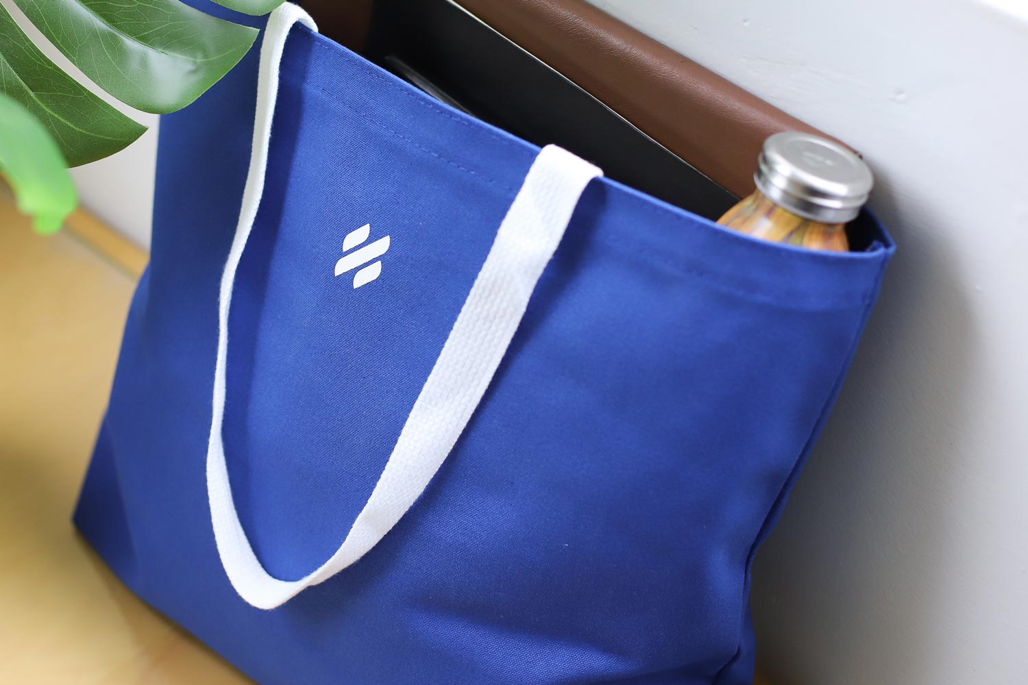 A Help Scout branded tote bag filled with work items like computer and water bottle.