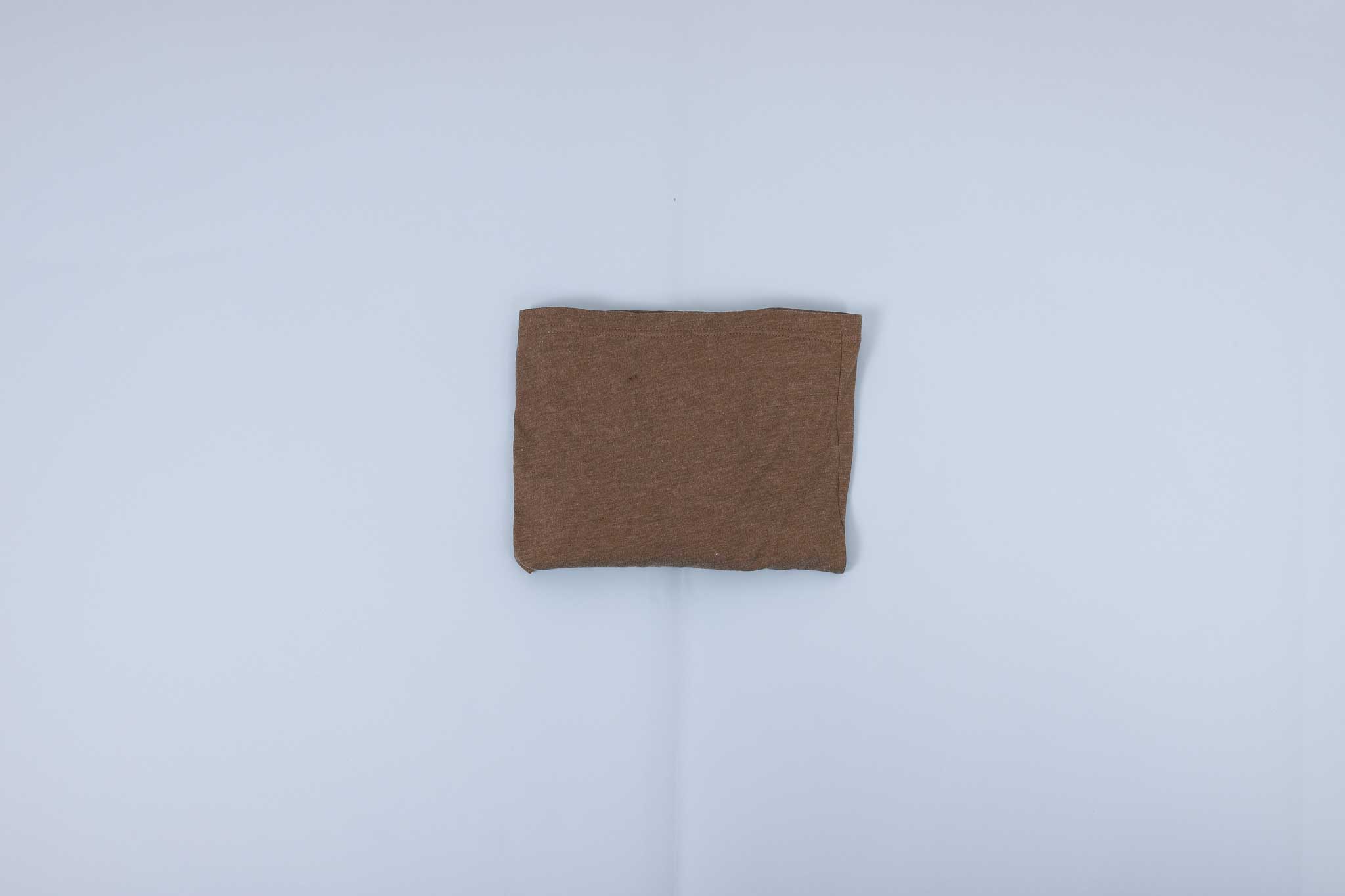 Olive long sleeve shirt folded into a rectangle on a light blue background