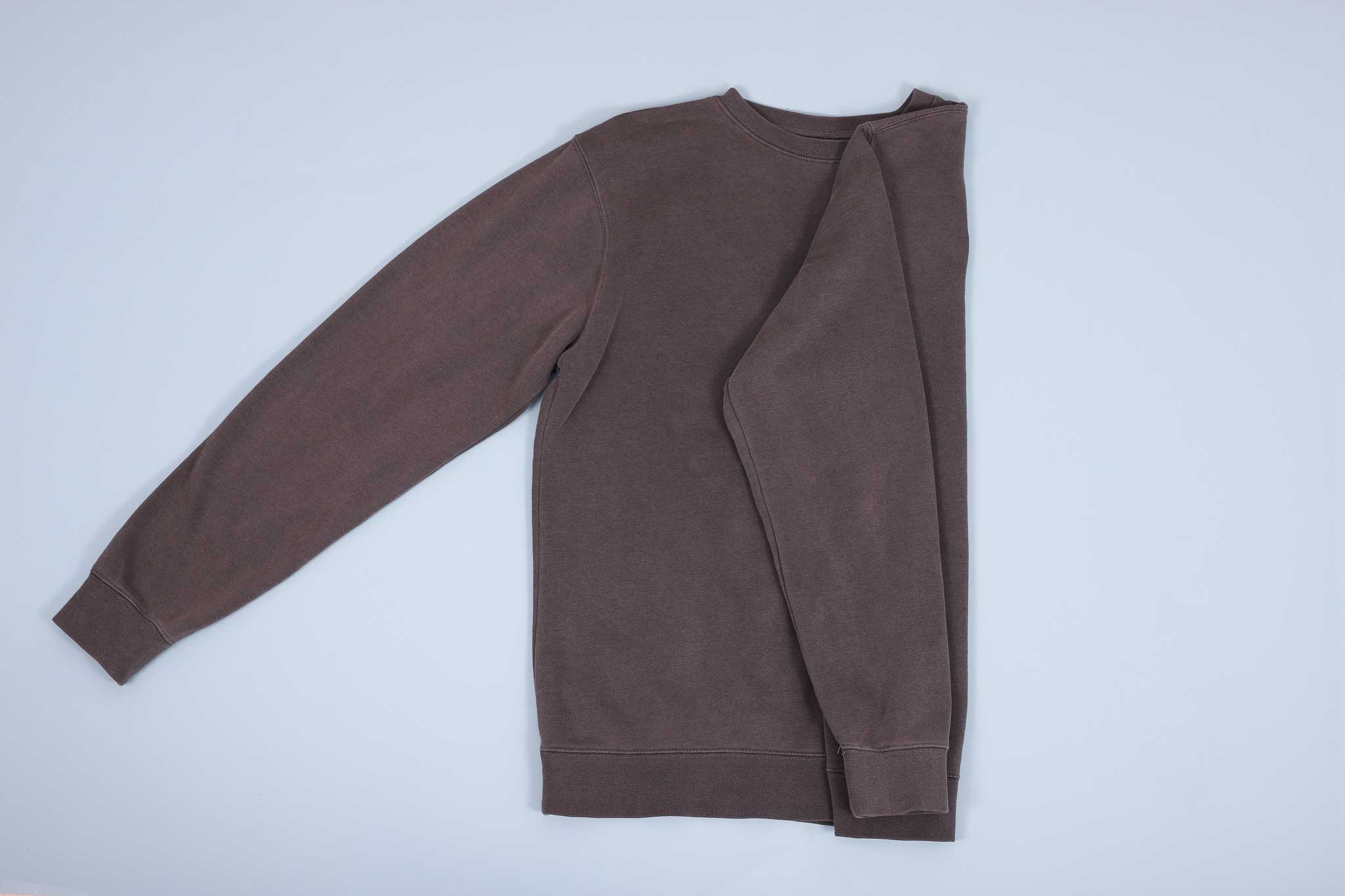 Grey sweater with sleeve folded in and then down towards the hem