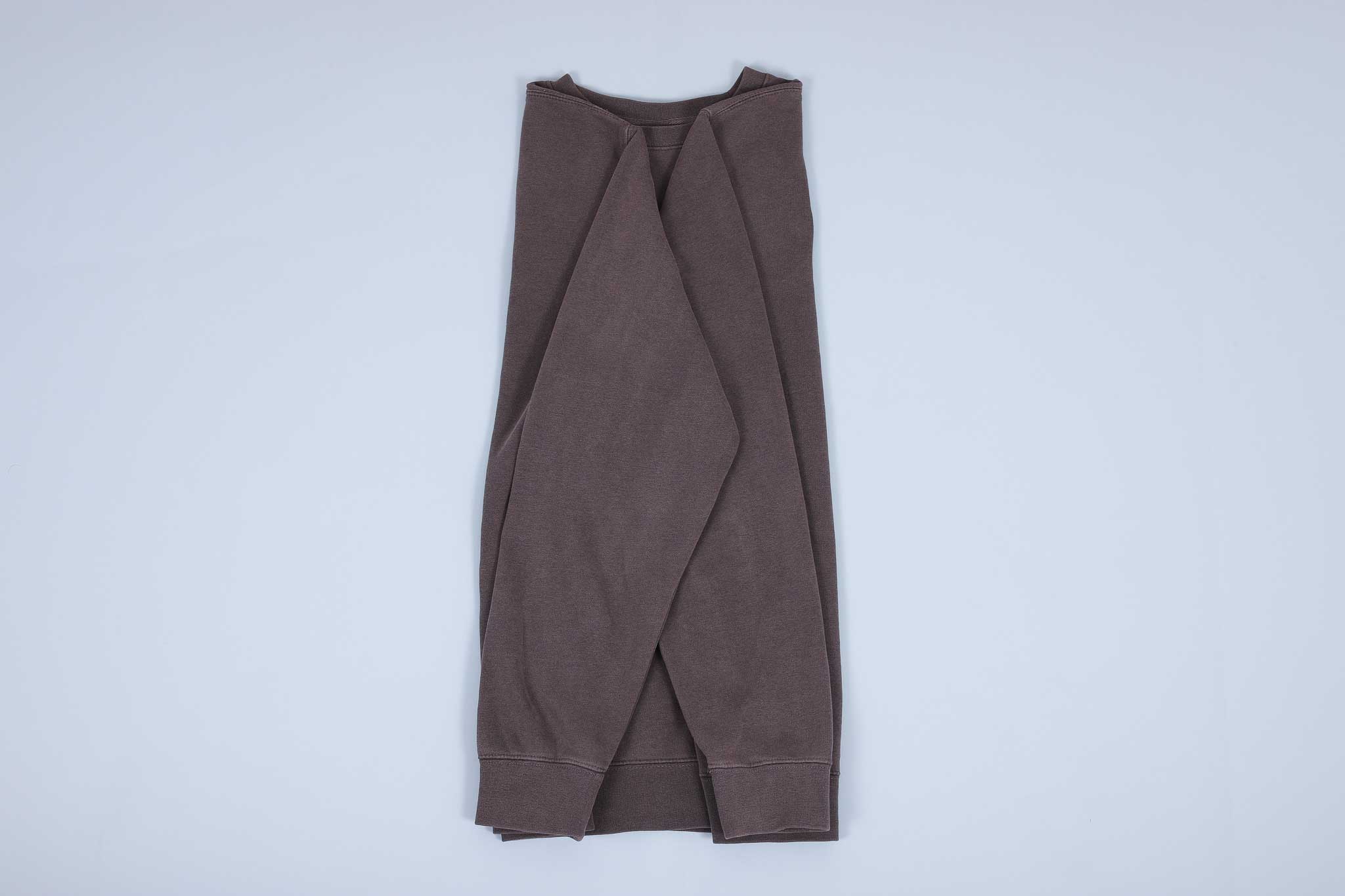 Grey sweater with both sleeves folded towards each other then away towards the hem