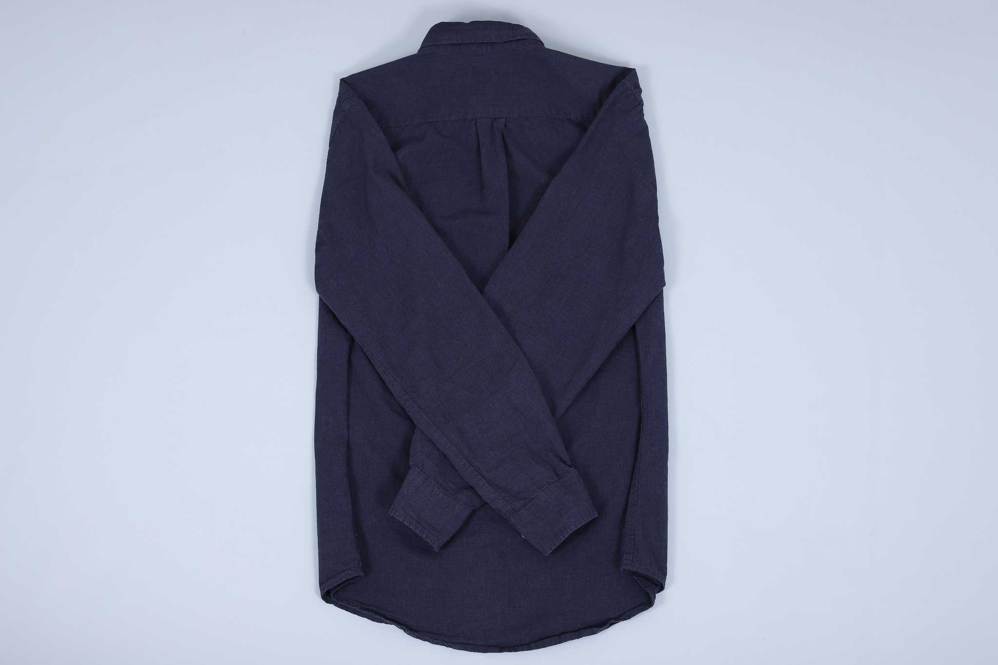 Navy buttoned up shirt with both sleeves crossed over each other on the back