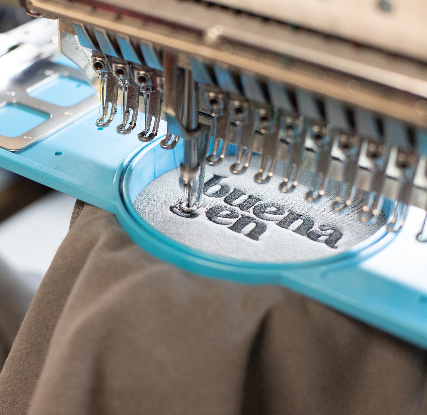 An embroidery machine embroiders a grey hoodie