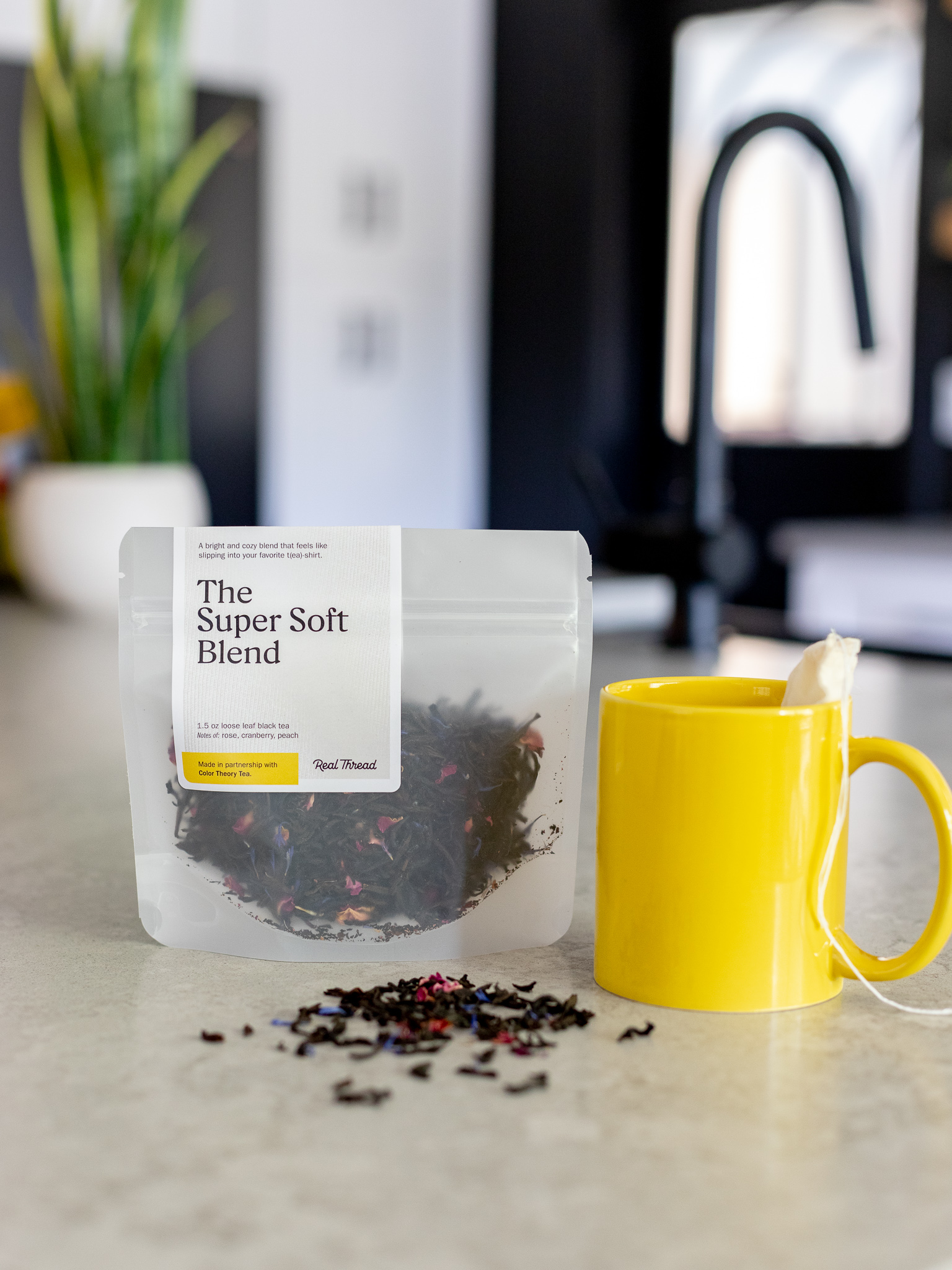 A package of Real Thread tea sits on a counter next to a mug